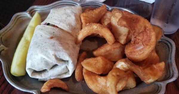 Mediterranean wrap with seasoned potato wedges.