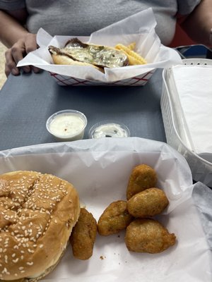 Cheese steak with fries in the back, mushroom Swiss burger with broccoli cheddar bites in front