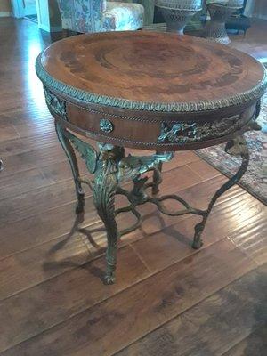 Round table inlay wood on top. Eagles support table. Has an eagle between legs on lower section of table.