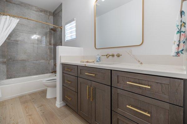 Bathroom with frames cabinets and gold features.  Bath/shower with beautiful large stone tiles.