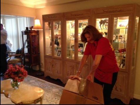 Uniformed staff member is breaking down a box after unpacking and setting up the china closet in client's new home.