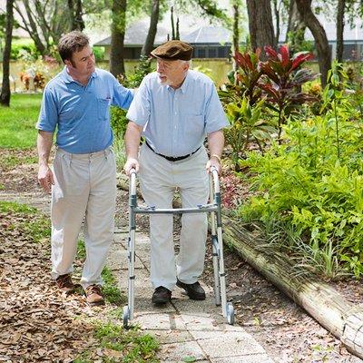 Elder Care Provider Walks With Senior Man