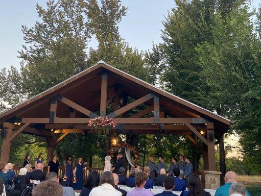 A wider shot of the outdoor pavilion used for the ceremony. The backdrop of trees is stunning.