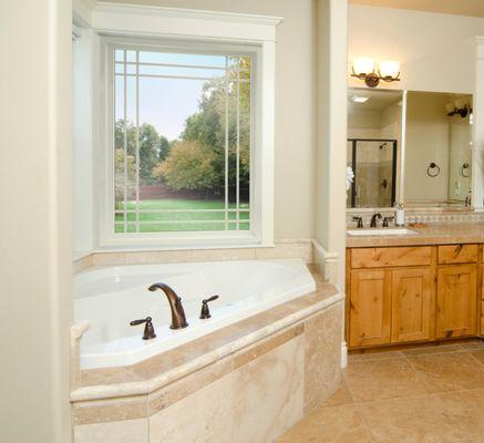 The EcoTek 1200 - 2200 Series Picture Window with Grids elevates this master bathroom with natural light and a scenic outdoor view. The grid