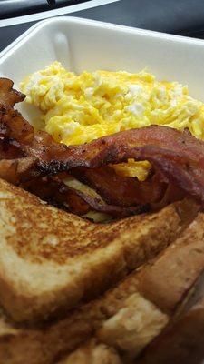 Scrambled eggs with cheese, wheat toast, and a side of bacon