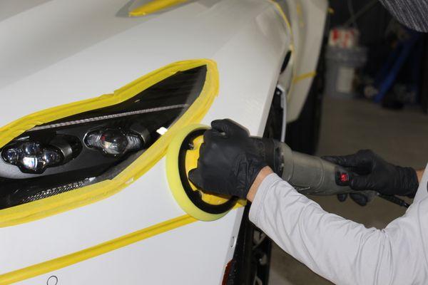 Portrayed in this picture is our shop technician  paint correcting a 2020 Aston Martin DB11 - removing all scratches and swirl marks.