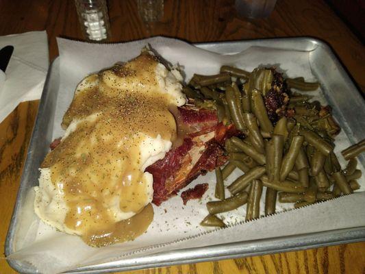 The $39 Fried Turkey Leg Dinner served on paper with plasticware, canned green beans and instant mashed taters