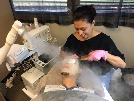 Exfoliating with the skin spatula, while steaming and masking a client