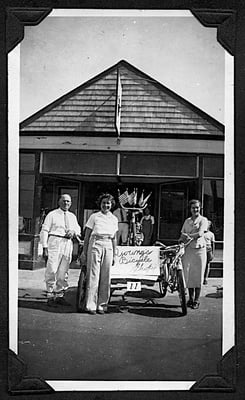 Harvey A. and Adelaide Young,  with their daughter Alice. July 4th 1938. In front of Harvey A. Young's Bicycle Shop, 6 Broad St., Nantucket