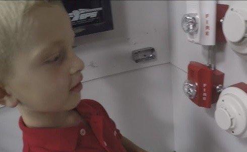 A kid looking at the brand new fire alarms Global Fire Tech installed!