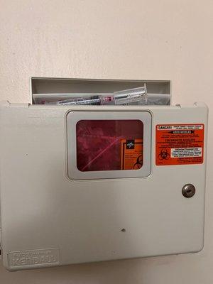 Needles sticking out of sharps container located in bathroom.