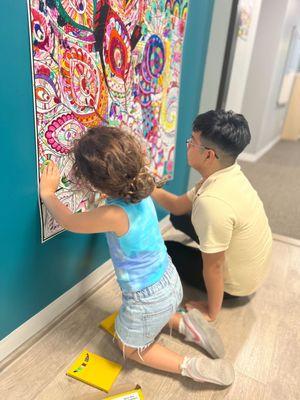 Academic Coach Miguel coloring our peacock poster with a student