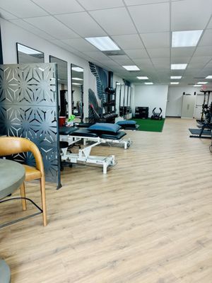 Large gym area with treatment tables, free weights, turf and a sled.