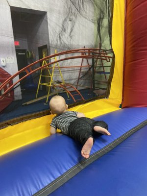 Inside the bounce house looking out at the metal obstacle course that kids can climb and learn the skills of balance and strength