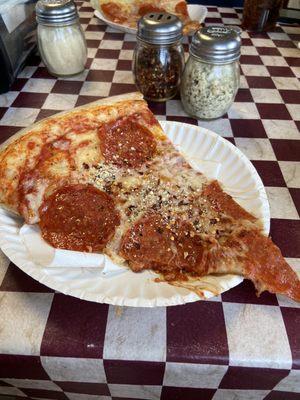 XL Pepperoni pizza slice with seasoned Parmesan cheese and crushed red pepper