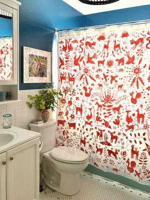 A handprinted shower curtain and blue walls complement each other.