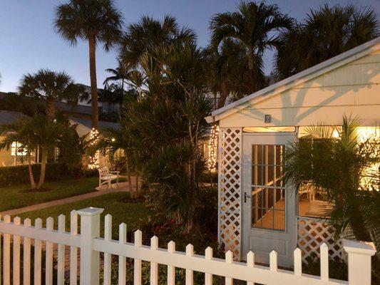 Romantic cottages at night with white lights in trees.