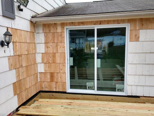 After installation of sliding glass doors, finished with cedar shake.