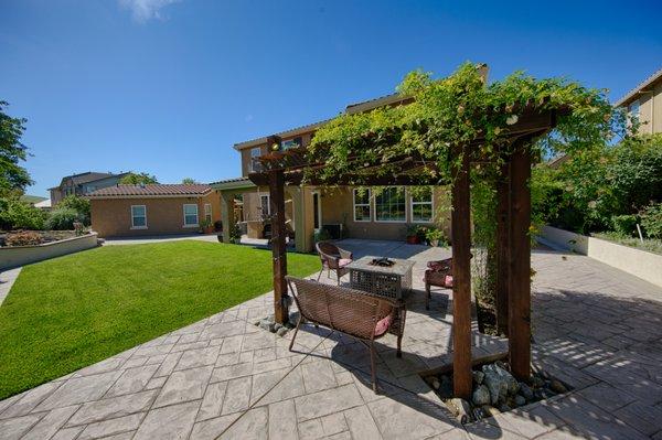 Gorgeous landscaped large lot backyard, with fruit trees, guest house, lush green lawn, with fire pit and pergola.