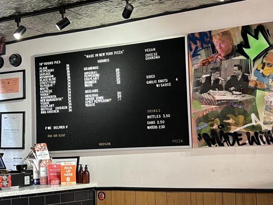 Price & menu for whole pizzas, drinks, and side items as of 14 April 2023. Also a bit of wall art.