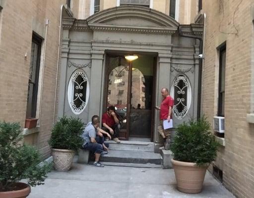 workers taking a smoke break in front of ny building. the smoke is trailing into the lobby