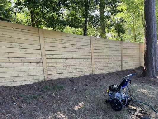 Privacy fence before being cleaned and treated to kill mold and algae growth