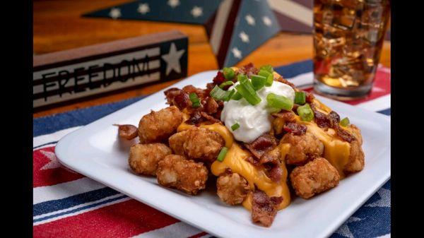 Tater tots fully-loaded with nacho cheese sauce, crispy bacon, sour cream, and chives.