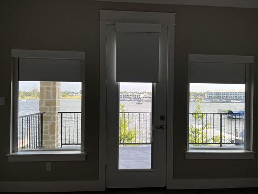 Motorized blackout roller shades in a main bedroom overlooking Lake Conroe.