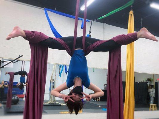 A student performs a lockless straddle back in the aerial silks