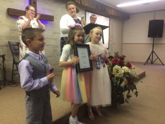 Children being honored for their Bible memorization and awarded for their performance in a tournament.