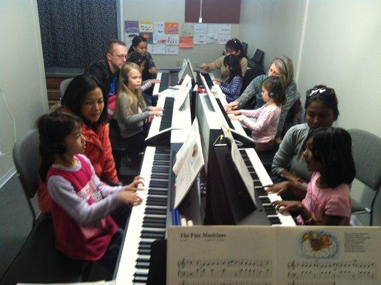 Parents and young children learn together at the keyboards during classes.