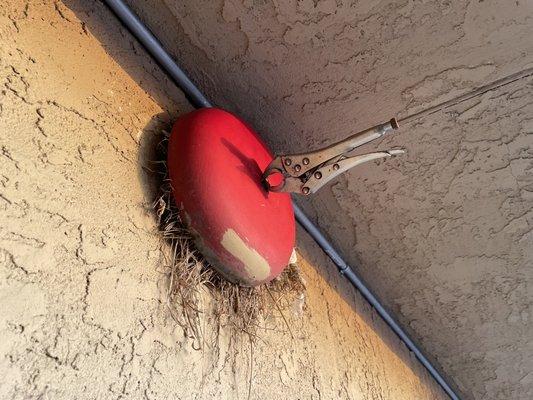 Fire alarm stabilized by a wrench. Also a birds nest.