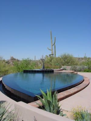 Tear-shaped wet edge pool tiled with black granite