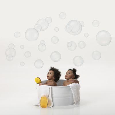 Babies in tub on white background looking at bubbles