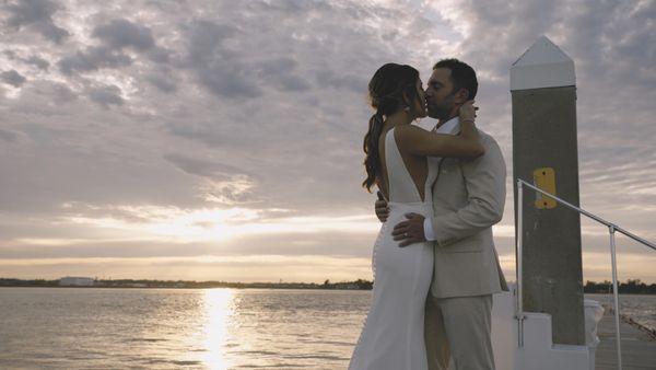 A passionate kiss on a dock at sunset.