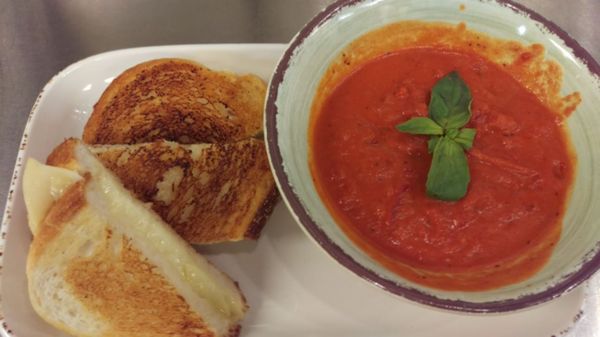 Three cheese grilled cheese and tomato soup, white cheddar, gruyere and Parmesan on artisan bread served with classic tomato soup