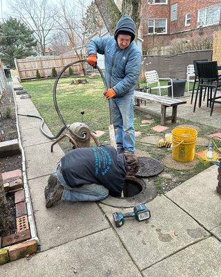 MD Plumbing rodding out catch basin in backyard.