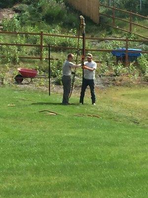 Installing a fence post with a pneumatic driver.