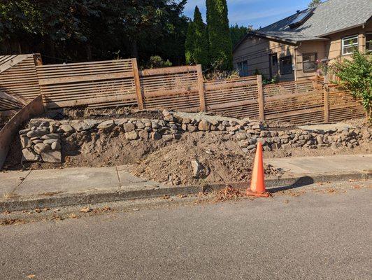 There are missing rocks in the wall, a pile of dirt blocking the sidewalk, and a pile of dead branches. We paid $1950 for this.