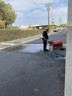 Employee washing out a sludge barrel in the alley