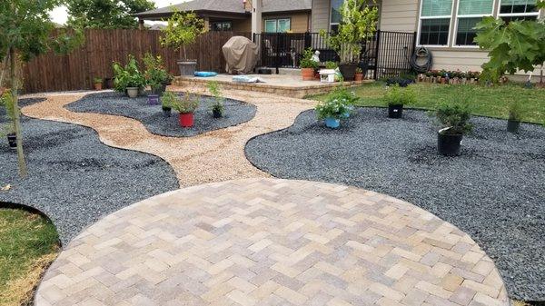 Patio made with pavers, black garden beds before the plants go in, and granite pathways. Taken from the informal patio toward the house.