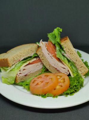 Smoked Turkey Sandwich - Smoke turkey slices, smoked gouda cheese, tomato slices, green leaf lettuce. Cranberry mayo on 9-Grain Bread.