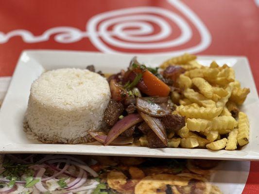 Lomo Saltado - Beef tenderloin slices, sautéed with onion, tomatoes, and other spices. Served with rice and French fries.