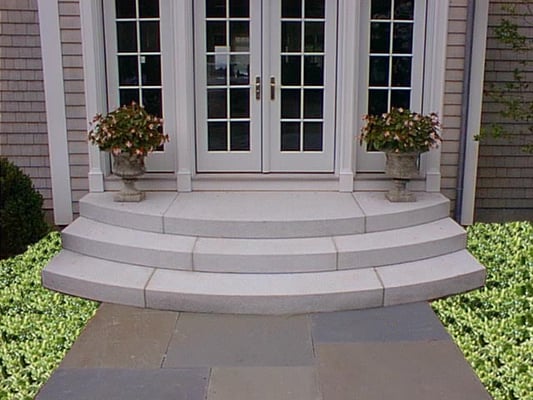 Solid Granite steps fabricated with our shop to a curved design.  Multiple Bluestone contrasts is used for the paving in front.