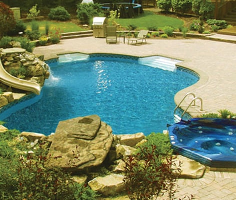 Artistic Landscapes LLC completes your poolside paradise with a gorgeous patio, waterfalls, walls and plantings.