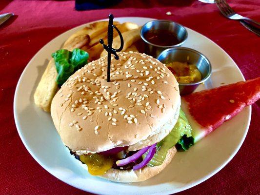 Bacon cheese burger with delicious fries, mustard and ketchup and watermelon wedge.