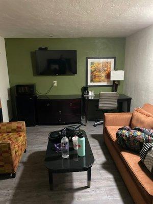 living area with tv, coffee maker, desk, microwave and mini refrigerator.