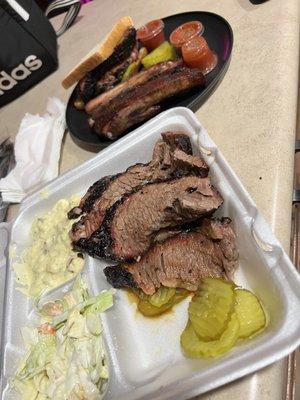 Brisket, cole slaw, potato salad (front)  Sliced brisket sandwich and pork ribs (back)