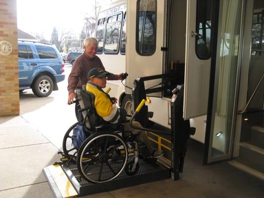 Handi-Wheels driver helping a passenger onto the bus.