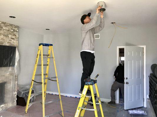 Cutout Sheetrock for wires, cans and  switches. Install another switch and make them turn on/off lights from two locations.